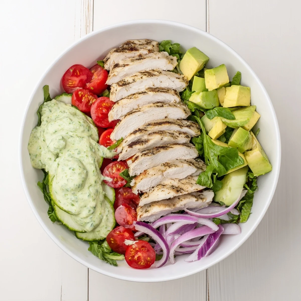 Vibrant creamy avocado grilled chicken salad bowl with fresh vegetables and tangy dressing