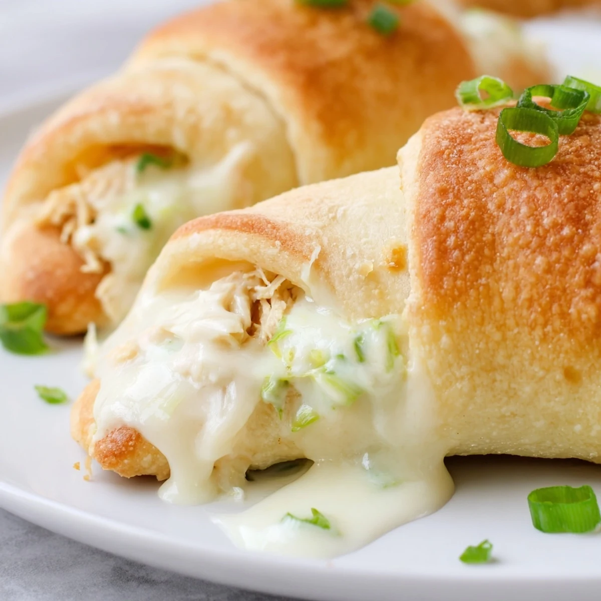 Golden baked chicken pillows wrapped in crescent dough drizzled with rich creamy parmesan sauce
