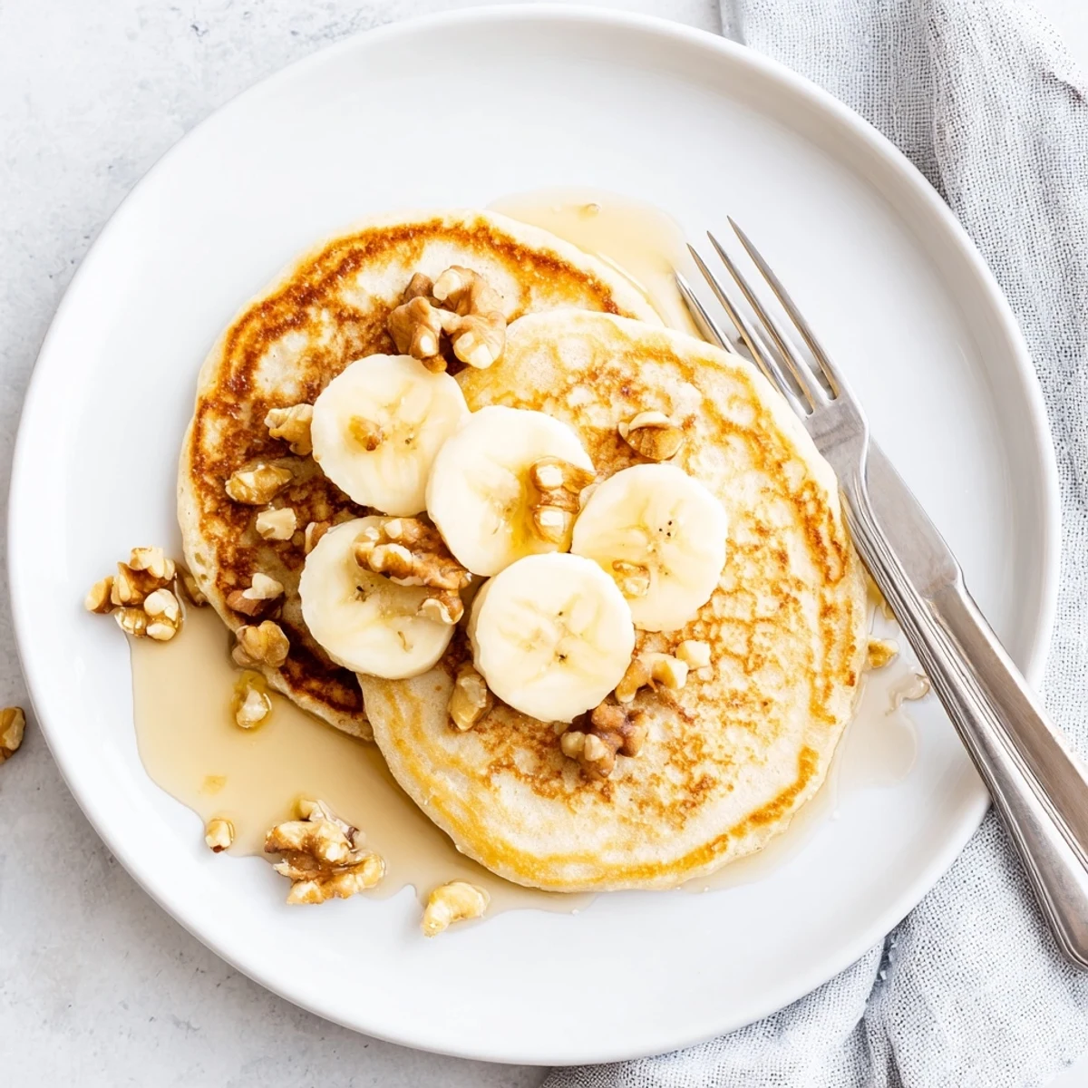 Stack of fluffy protein banana pancakes topped with fresh berries and maple syrup on a white plate