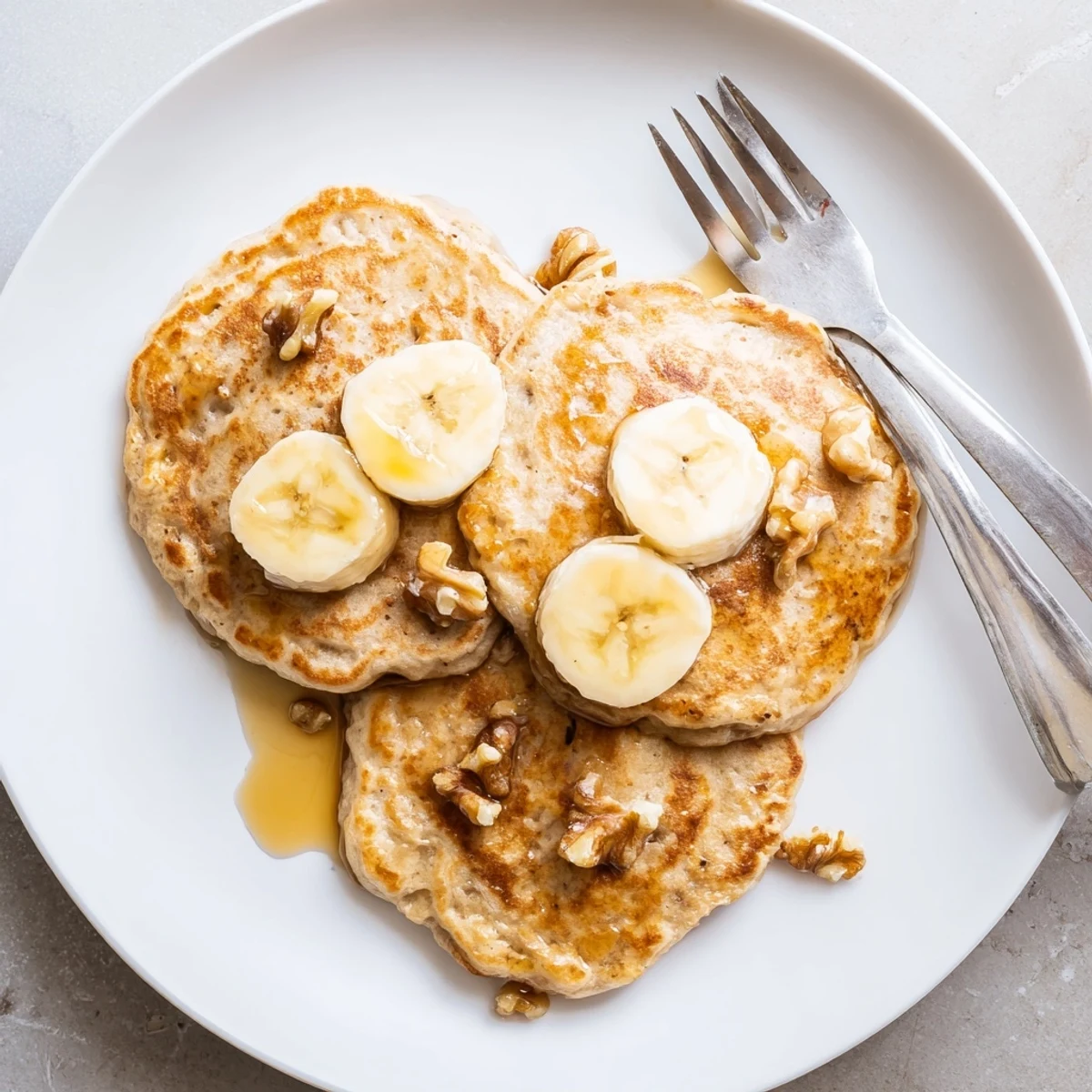 Golden brown protein banana pancakes cooking in a skillet with visible steam rising from the surface