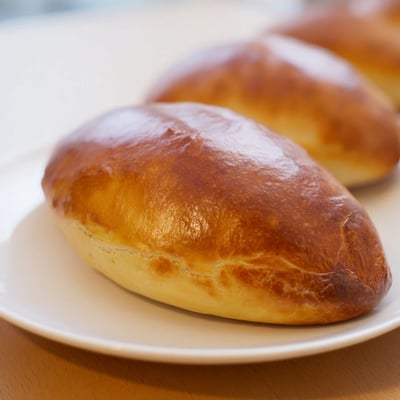 Close-up of a halved Cheesy Egg and Cheese Piroshki revealing fluffy eggs and melted cheese filling.